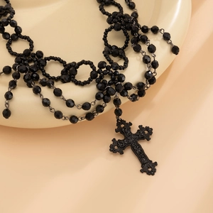 Macro-opname van gotische gelaagde zwarte kralenketting met een sierlijk kruis-detail