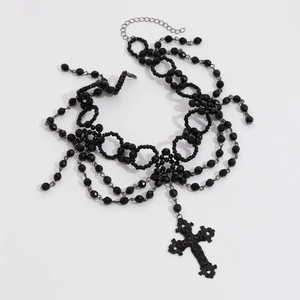 Detail van een meerlagige zwarte kralen Gothic ketting met een grote versierde kruishanger
