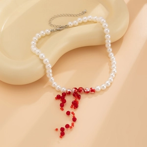 Detail of beaded necklace featuring white pearls, red crystal tassels, and a lobster clasp