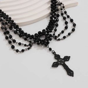 Detail van een gothische gelaagde zwarte kralenketting met een grote kruis hanger