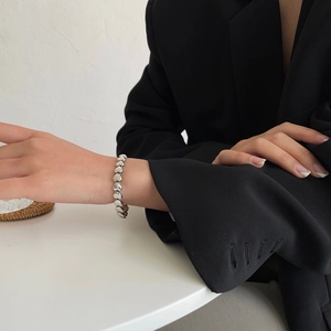 Detailaufnahme eines silbernen Herz-Gliederarmbands mit hochglanzpolierter Metalltextur