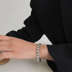 Minimalistisches Herzgliederarmband in Silber, getragen zu einem schicken Blazer