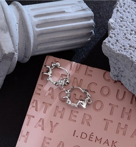 Macro detail of silver irregular lava texture earrings on a pink artistic backdrop