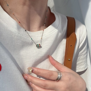 Close-up of rainbow enamel tube pendant necklace and silver double-ring worn by a model