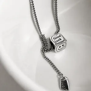 Dettaglio macro della collana d'argento con ciondolo a cubo Good Luck e incisione smiley