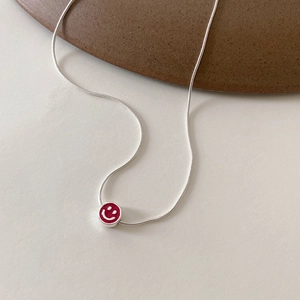 Vue rapprochée du pendentif smiley en émail rose sur une chaîne serpent argentée