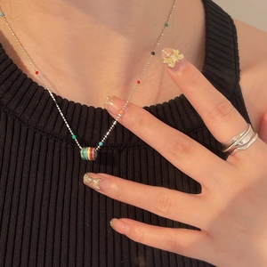 Detail of colorful enamel bead pendant necklace on a silver chain and minimalist silver ring