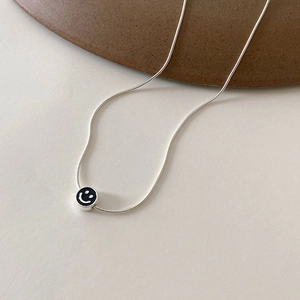 Vue détaillée de la chaîne serpent argentée et du pendentif rond avec visage souriant