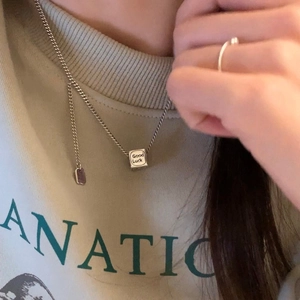 Collana chic con pendente quadrato argento e incisione Good Luck indossata da donna