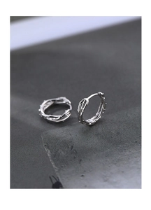 Détail macro de boucles d'oreilles créoles argentées avec motif de vigne torsadée