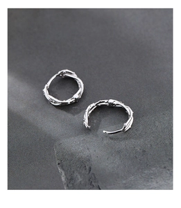Gros plan de boucles d'oreilles créoles épines en argent avec texture de vigne naturelle