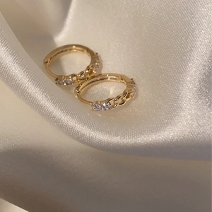 Exquisite vergoldete Kettenohrringe mit weißem Zirkon auf elegantem weißem Seidenstoff