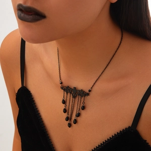 Close-up of gothic black bat necklace with crystal tassels on female model neck