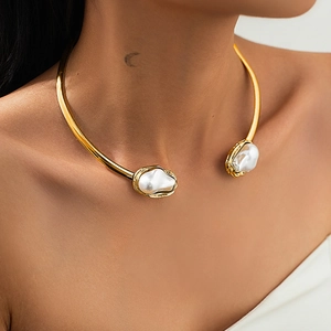 Vue détaillée d'un collier rigide doré avec deux perles baroques sur le cou du mannequin