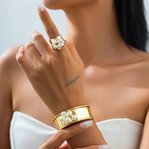 Dettaglio del set bracciale rigido dorato e anello con decorazioni di perle raffinate