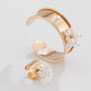 Dettaglio del bracciale rigido dorato e dell'anello con grappoli di perle bianche