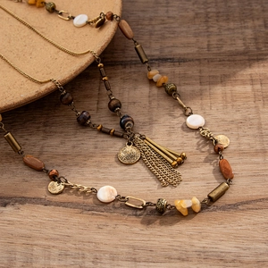 Detail of vintage bohemian long necklace with bronze chains, wood beads and metal tassels