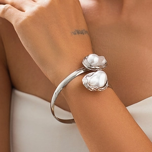 Détail d'un bracelet ouvert argenté orné de deux grandes perles baroques serties en nid