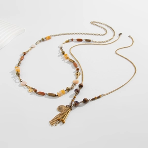 Detail view of multilayer beaded necklace with star tassels and antique gold relief medal