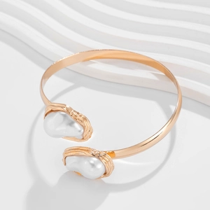 Détail du bracelet doré ouvert avec deux perles baroques et monture texture lave