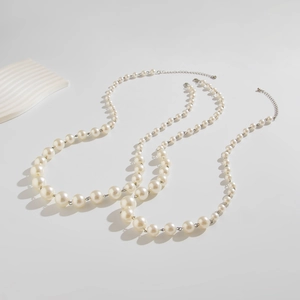 Detail of layered white imitation pearl necklaces with adjustable metal lobster clasps