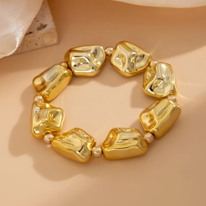 Detalle macro de pulsera de cuentas doradas con dijes metálicos de textura irregular única