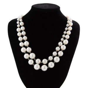 Detail view of double-layered faux pearl necklace on black velvet display stand