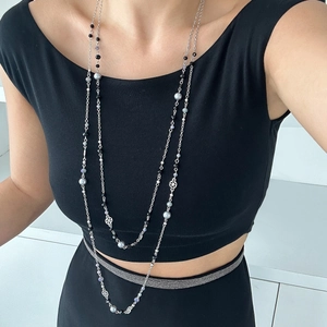 Detail of layered silver star necklace with black and blue faux pearls on a black top