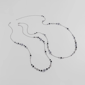 Detailed macro view of layered long necklace with grey faux pearls and star pendants