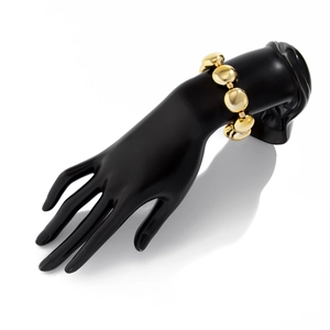 Vue détaillée du bracelet à grosses perles dorées sur un modèle de main
