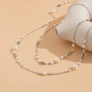 Close-up of long pearl necklace with silver star pendants and vintage metallic chain