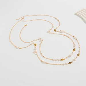 Detail view of long gold layered necklace with faux pearls and hollow metal star charms