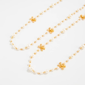 Detail of elegant gold bow accents and white pearls on this long layered necklace
