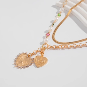 Makroaufnahme einer goldenen Herz-Halskette mit Perlen, Strass und bunten Perlen