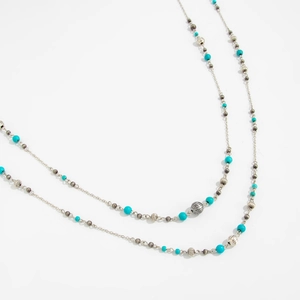 Detail of silver layered necklace featuring turquoise beads and ribbed metal pumpkin charms