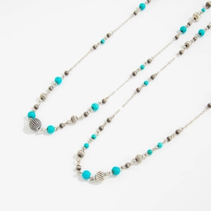 Detail of bohemian long necklace featuring turquoise beads and striped silver metal accents
