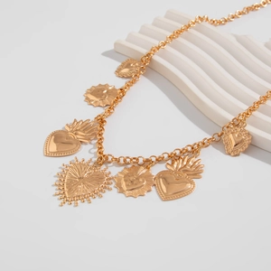Detail einer Vintage-Goldkette mit barocken Herzanhängern auf weißem Stufendisplay