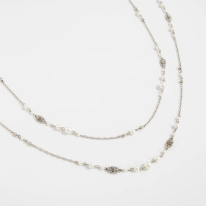 Detail of vintage long faux pearl necklace with silver flower charms and star tassels