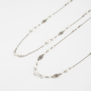 Detail of silver long necklace featuring faux pearls and hollow flower metal links