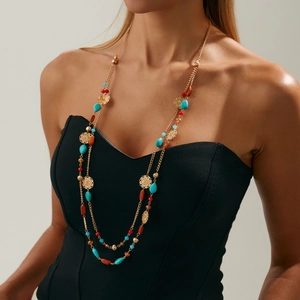 Detail of bohemian layered necklace with turquoise beads and golden floral charms