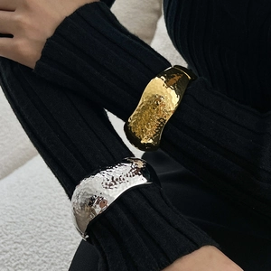 Detailed view of wide hammered texture metal cuffs in gold and silver finish