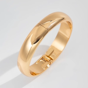 Close-up of golden liquid metal textured wide bangle with smooth mirror finish and spring hinge
