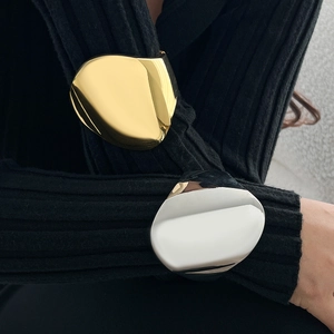 Close-up of gold and silver irregular mirror-polished cuff bracelets on a black sleeve