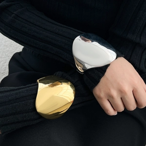 Detailed view of high-shine gold and silver irregular metallic wide bangle bracelets