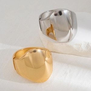 Macro detail of chunky irregular polished gold and silver metal bangles on stone