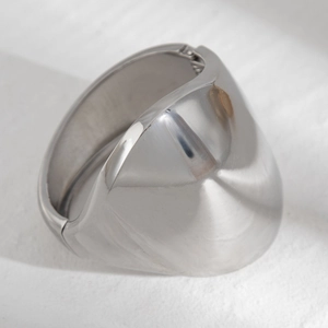 Detailed view of silver minimalist metal cuff bracelet with spring hinge on stone surface