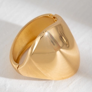 Detailed macro view of wide golden polished metal bracelet with mirror finish
