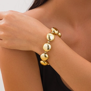 Pulsera de cuentas doradas pulidas con grandes cuentas de metal planas en la muñeca
