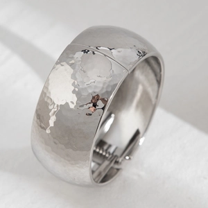 Detailed view of wide silver hammered texture metal bracelet with spring hinge closure