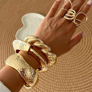 Golden liquid metal cuff bracelets and layered ring set with hammered geometric texture